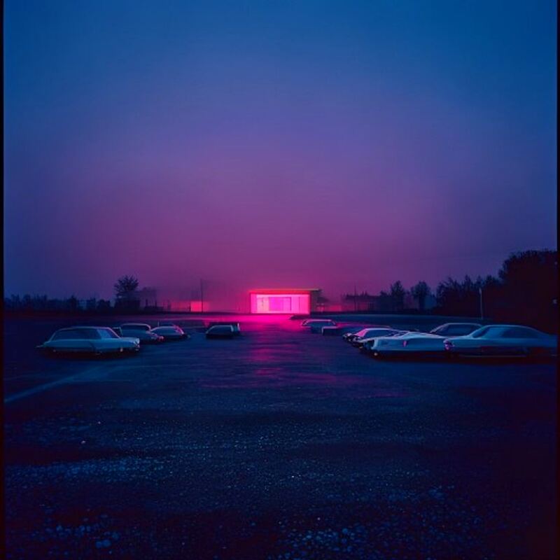 Late-night parking lot with cars and a distant neon glow against a deep blue sky